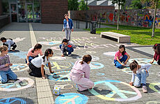 Kinder malen mit Kreide Friedenssymbole auf die Straße