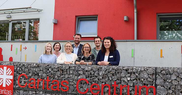 Sieben Frauen und Männer stehen vor dem Caritas-Gebäude.