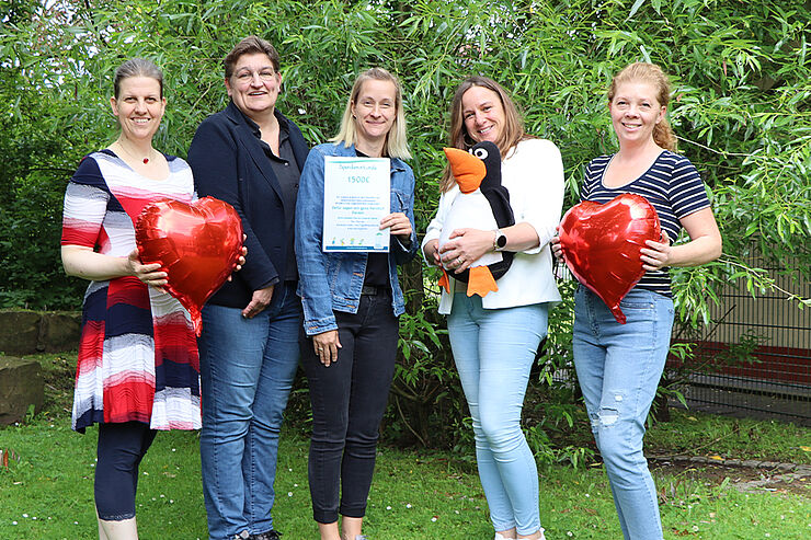 Fünf Frauen mit Herzluftballons und Urkunde stehen auf einer Wiese.