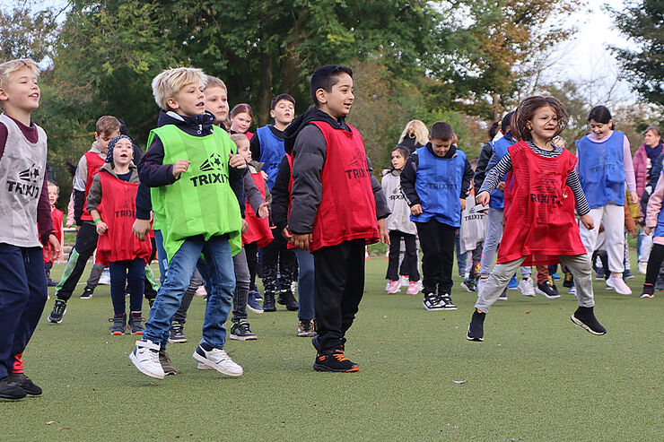 Mehrere Kinder in bunten Trikots springen in die Luft.