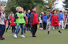 Mehrere Kinder in bunten Trikots springen in die Luft.