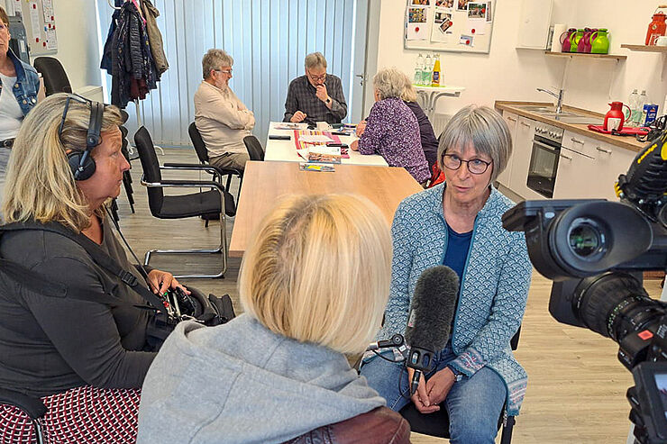 Frau spricht in Mikrofon einer anderen Frau.